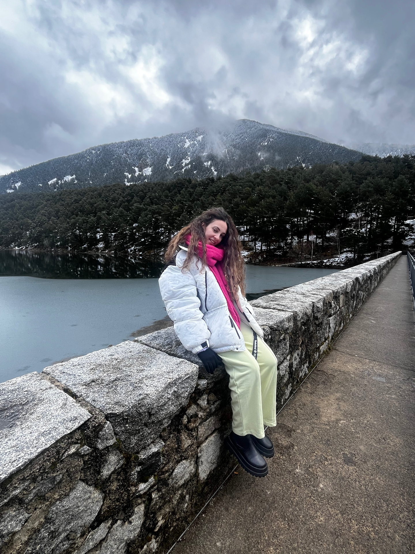 Ella sentada en el puente de piedra junto al lago