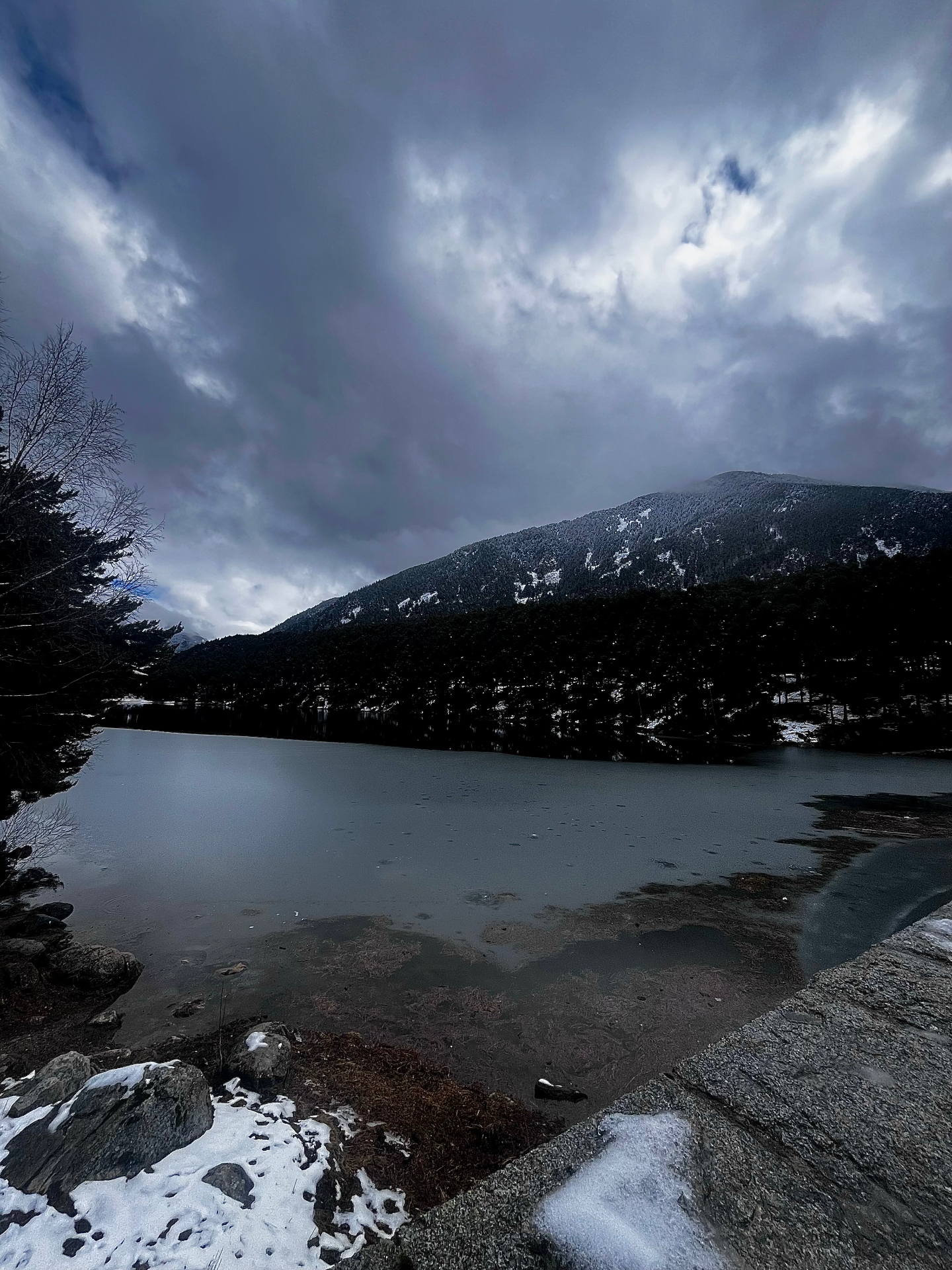 Lago helado bajo cielo tormentoso de montaña