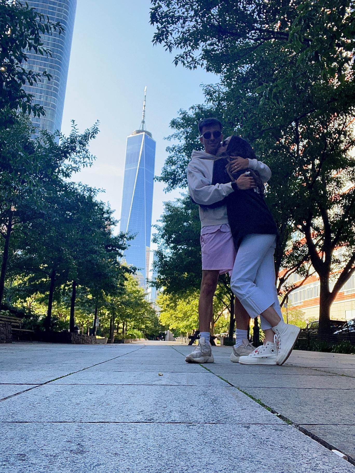 Abrazo bajo el One World Trade Center entre los árboles del West Side