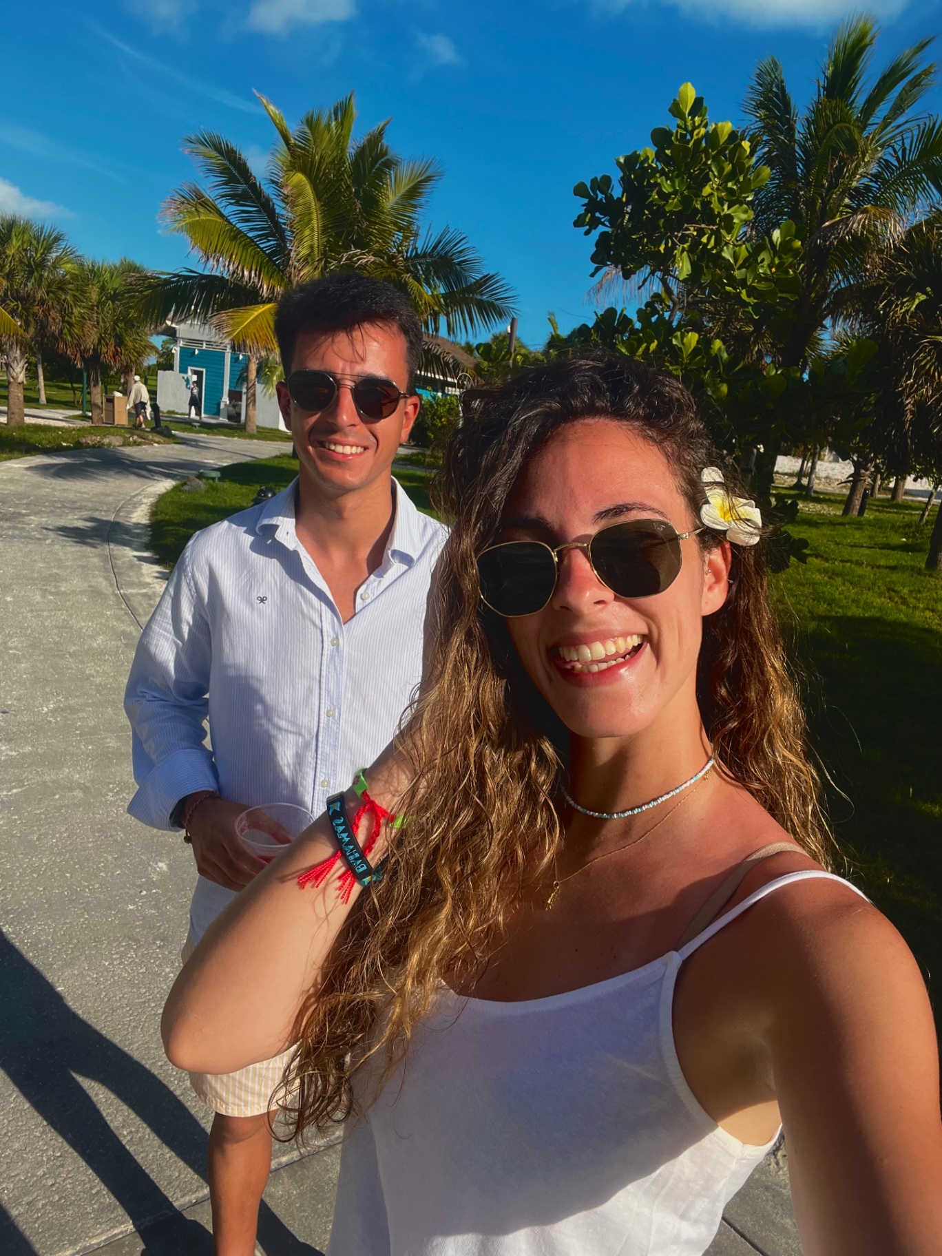 Selfie de pareja paseando por Ocean Cay con flor en el pelo y palmeras al fondo