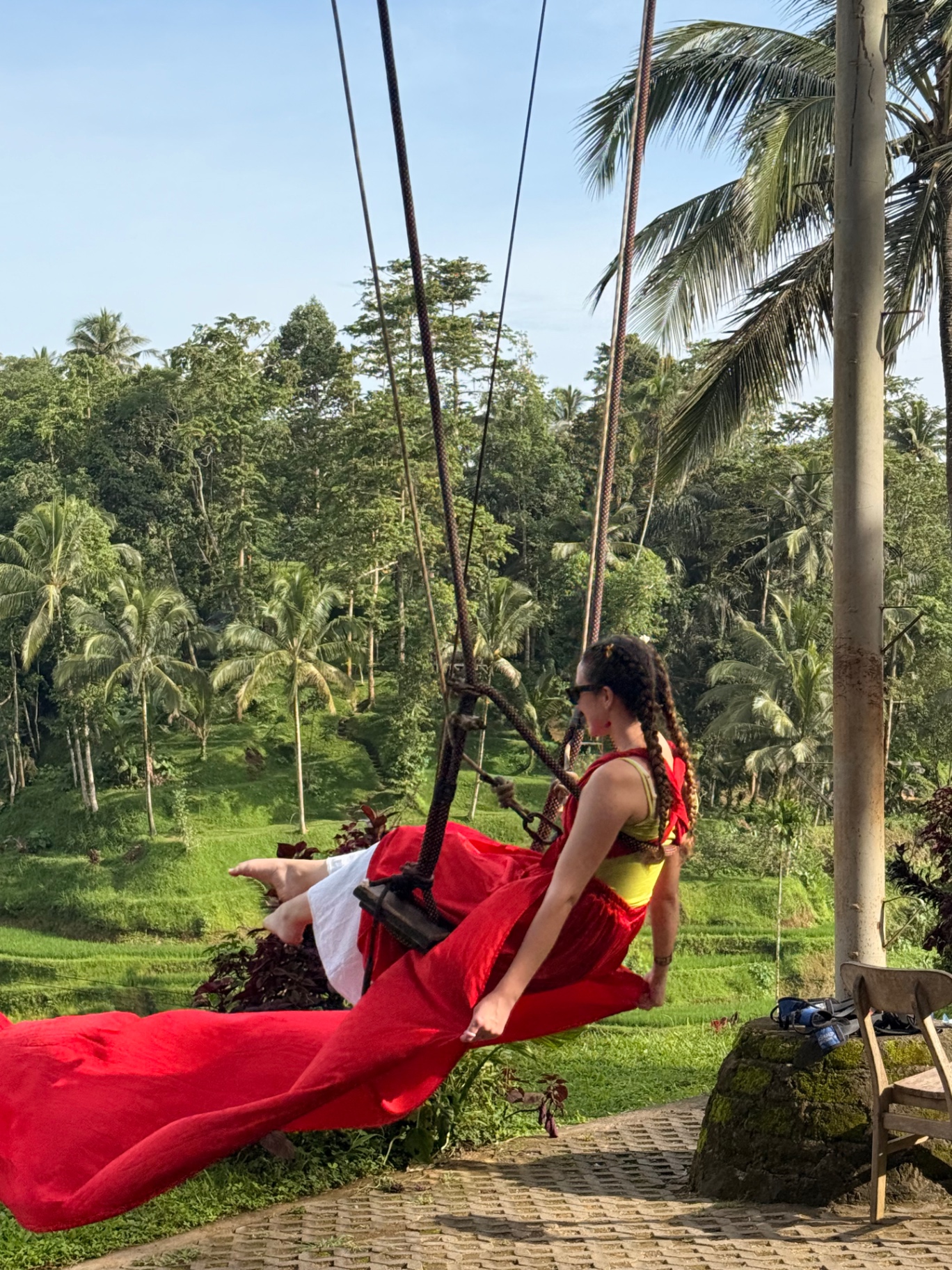 Columpio balinés sobre la selva con vestido rojo al vuelo