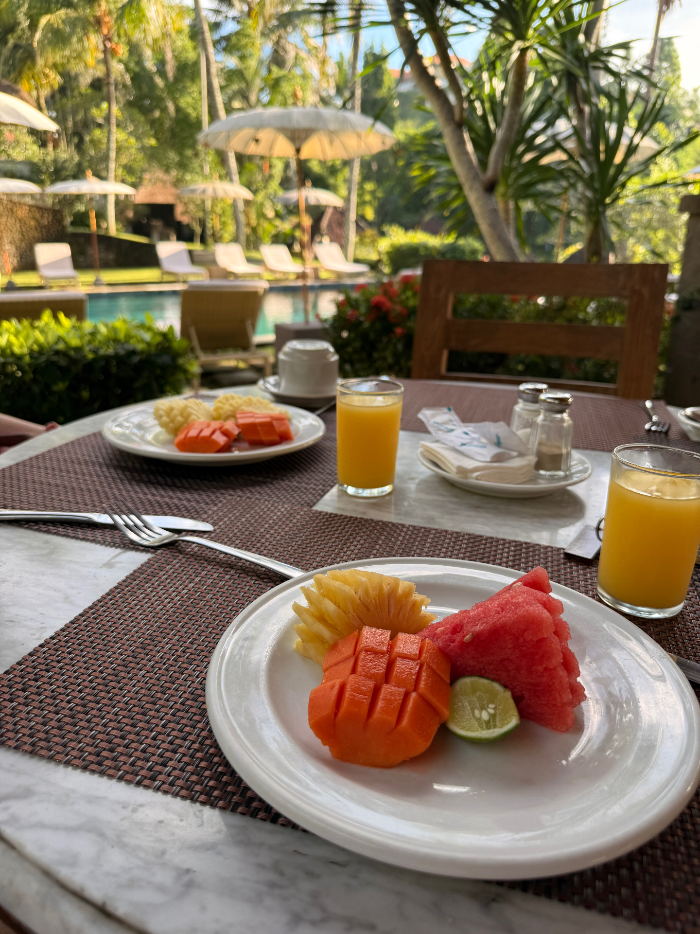 Desayuno de fruta tropical y zumo de naranja junto a la piscina